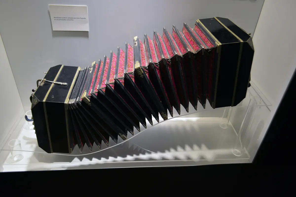 A bandoneon player's hands working the instrument's keys in a warmly lit room